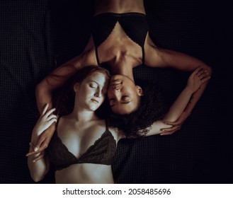 Couple Of Homosexual Women In Lingerie Lying Eyes Closed In The Bed. Multiracial Lesbians Relaxin In The Bed, Dark Moody Image. 