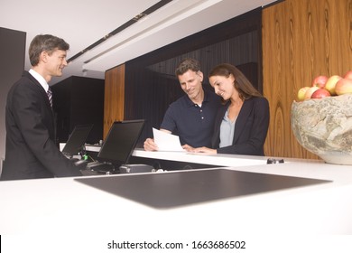 Couple At Hotel Reception Reading Bill