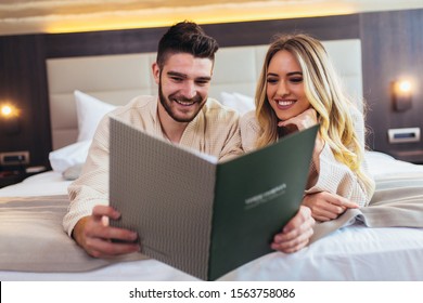 Couple In Hotel Room Reading Room Service Menu Together In Bed