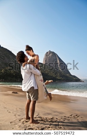 Couple hugging on beach, man lifting woman, Rio de Janeiro, Brazil