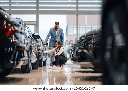 A couple is inspecting different vehicles within a showroom, discussing their choices and preferences, symbolizing the intricacies involved in deciding on the perfect car to purchase together.