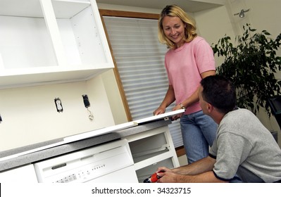 Couple Installing Kitchen Cabinet