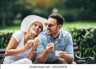 Couple joking and having fun while eating an ice cream in the park.