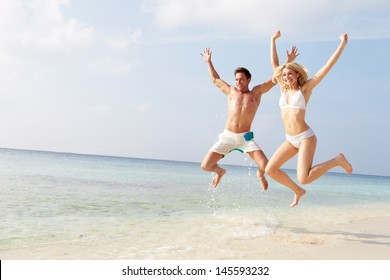 Couple Jumping In The Air On Tropical Beach