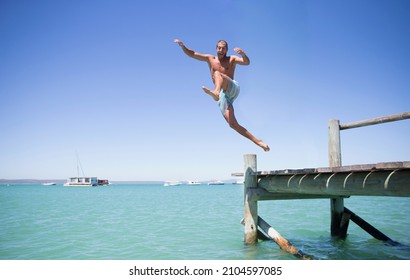 Couple jumping off wooden dock into water - Powered by Shutterstock