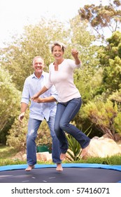 Couple Jumping On Trampoline In Garden