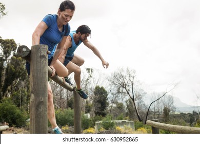 Couple jumping over the hurdles during obstacle course in boot camp - Powered by Shutterstock