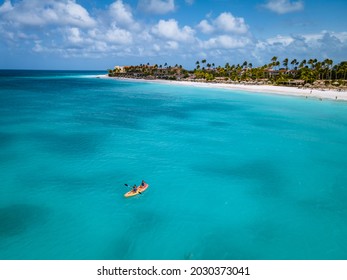 Couple Kayaking In The Ocean On Vacation Aruba Caribbean Sea, Man And Woman Mid Age Kayak In Ocean Blue Clrea Water White Beach And Palm Trees Aruba