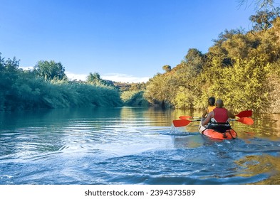 Couple kayaking on a reed-lined river in Sanlucar de Guadiana, Huelva, Spain. Natural area of the Ribera Grande de La Golondrina at its mouth into the Guadiana River.