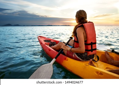 Pareja haciendo kayak juntos. Hermosa pareja joven kayak en el lago juntos y sonriendo al atardecer