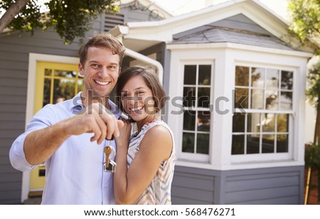 Couple With Keys Standing Outside New Home