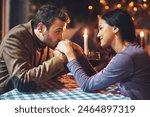 Couple, kiss and hands with romance on date in restaurant for anniversary, honeymoon and love with candle. People, happy and dinner with fine dining for support, trust and commitment in marriage