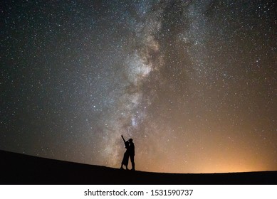 Couple Kiss Standing On The Dunes Of Sahara Desert Under A Sky Full Of Stars And The Milky Way. Love And Galaxy.