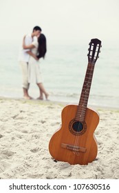 Couple Kissing At The Beach And Guitar.