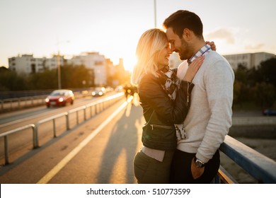 Couple kissing dating on bridge during sunset