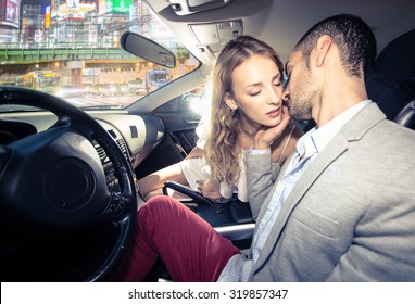 couple kissing each other in the car, traffic jam in the night visible from the street. 