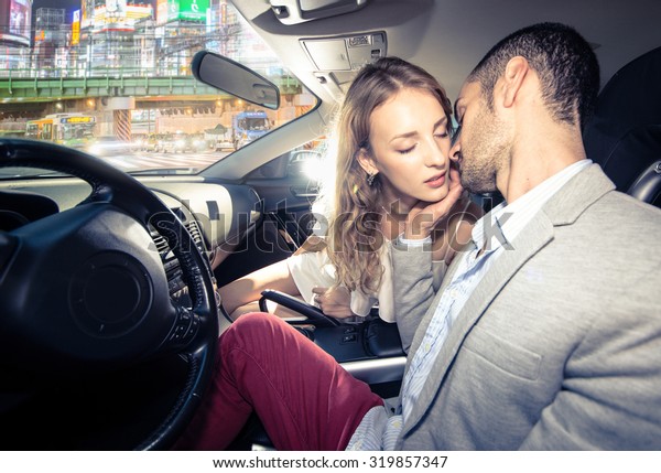 couple kissing each other in the car,\
traffic jam in the night visible from the street.\
