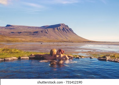 Couple kissing in natural hot bath with the spectacular Icelandic scenic view of the mountain and ocean coast, Westfjords Iceland