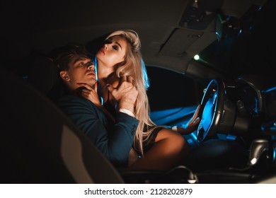 Couple kissing at night in the car. Gentle night photo session in the city. Summer vacation for lovers.