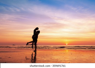 Couple kissing on the beach with a beautiful sunset in background, man lifting the woman - Shutterstock ID 359691761