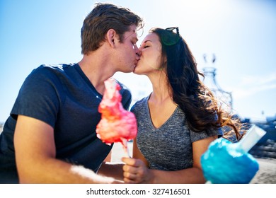 couple kissing on romantic date with cotton candy on sunny summer day shot with lens flare and thin depth of field
