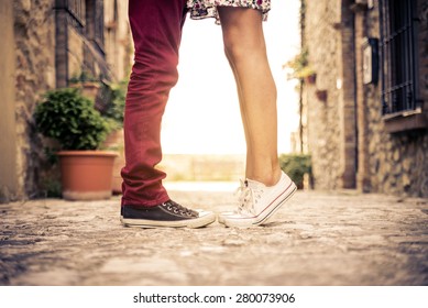 Couple kissing outdoors - Lovers on a romantic date at sunset,girls stands on tiptoe to kiss her man - Close up on shoes