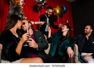 Couple kissing at a party with people toasting in background
