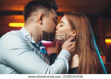 Couple kissing sitting on sofa at home at night. Dating.