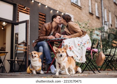 A couple is kissing in a street cafe. Corgi dogs are sitting nearby. - Powered by Shutterstock