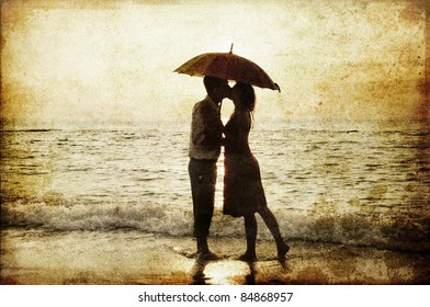 Couple kissing under umbrella at the beach in sunset. Photo in old image style.