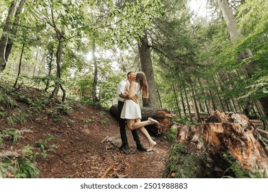 A couple is kissing in the woods. Scene is romantic and intimate. The couple is embracing each other, and the setting is a forest with trees and a log - Powered by Shutterstock