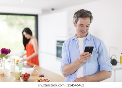 couple in the kitchen at the morning man texting on his phone - Powered by Shutterstock