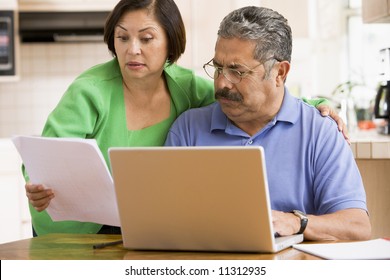 Couple In Kitchen Working On Personal Finances, Looking Worried