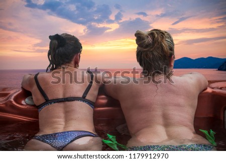 couple of ladies on vacations having fun and enjoying the benefits of the outdoor hot tub in front of sunset