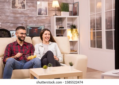 Couple Laughing So Hard While Watching A Movie On Tv And Eating Chips.