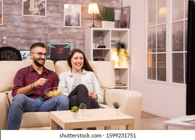 Couple Laughing So Hard While Watching A Movie On Tv And Eating Chips.