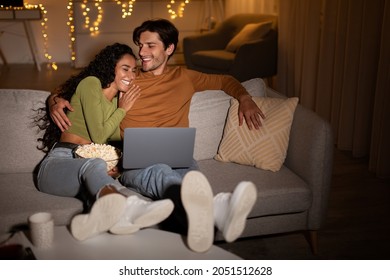 Couple Laughing Watching Comedy Movie On Laptop Online Relaxing And Having Fun Sitting On Sofa At Home At Night. Weekend Leisure And Entertainment Concept. Selective Focus