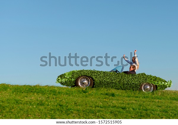 Couple in leaf covered sports\
car