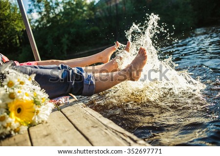 Couple legs in the water splashing with bouquet of  flowers