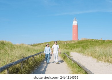 A couple leisurely walks along a path next to a charming lighthouse on the picturesque island of Texel, Netherlands. man and woman at The iconic red lighthouse of Texel Netherlands - Powered by Shutterstock