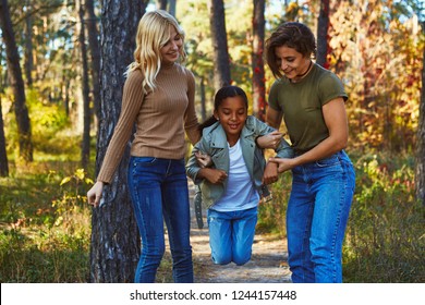 A Couple Of Lesbian Ladies Having Fun In The Autumn Park With Their Teenage Daughter. The Young Women Entertaining The Kid. The Girl Has The Help Of Her Female Parents As She Attempts To Jump High.