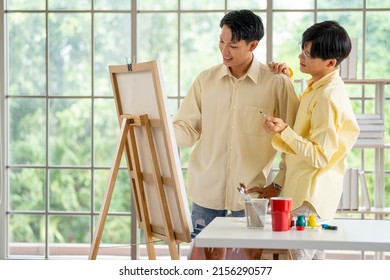 Couple lgbt or gay men enjoy to draw or paint the picture together in living room with glass window and day light.