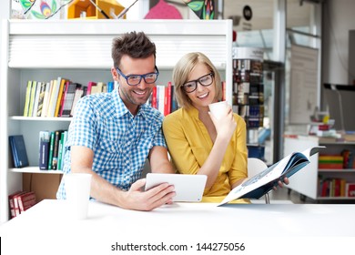 Couple In Library Working With Digital Tablet