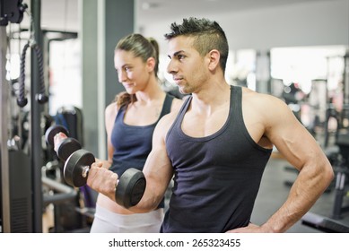 Couple Lifting Weights With Natural Light At Gym