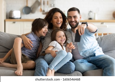 Couple little kids sitting on sofa making self-portrait using smartphone, husband holding gadget spend time having fun on-line with children and wife laughing enjoy weekend, internet app usage concept - Powered by Shutterstock