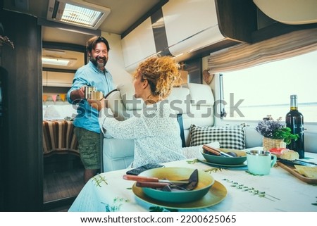 Couple living off grid inside a modern luxury camper van and enjoy travel lifestyle. People on vacation with home vehicle. Concept of van life for man and woman having lunch inside a motor home