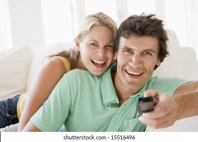 Couple in living room holding remote control smiling