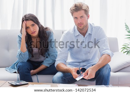 Couple looking anxious while doing their accounts together in the living room