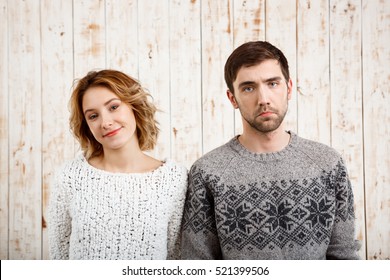 Couple Looking At Camera Over Wooden Background. Girl Smiling, Man Sad.