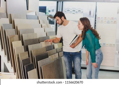 Couple looking ceramic and tiles for their new home floor. They are choosing in furnitures store